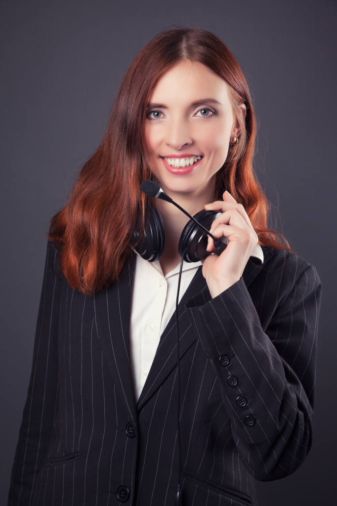 beautiful business woman with headphones against dark grey background